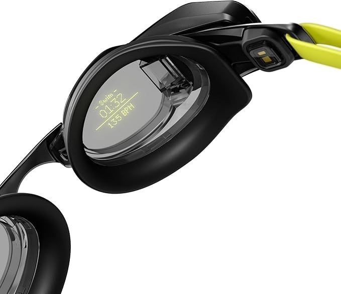Close-up of black swimming goggles with a digital display on the lens showing swim time and BPM.