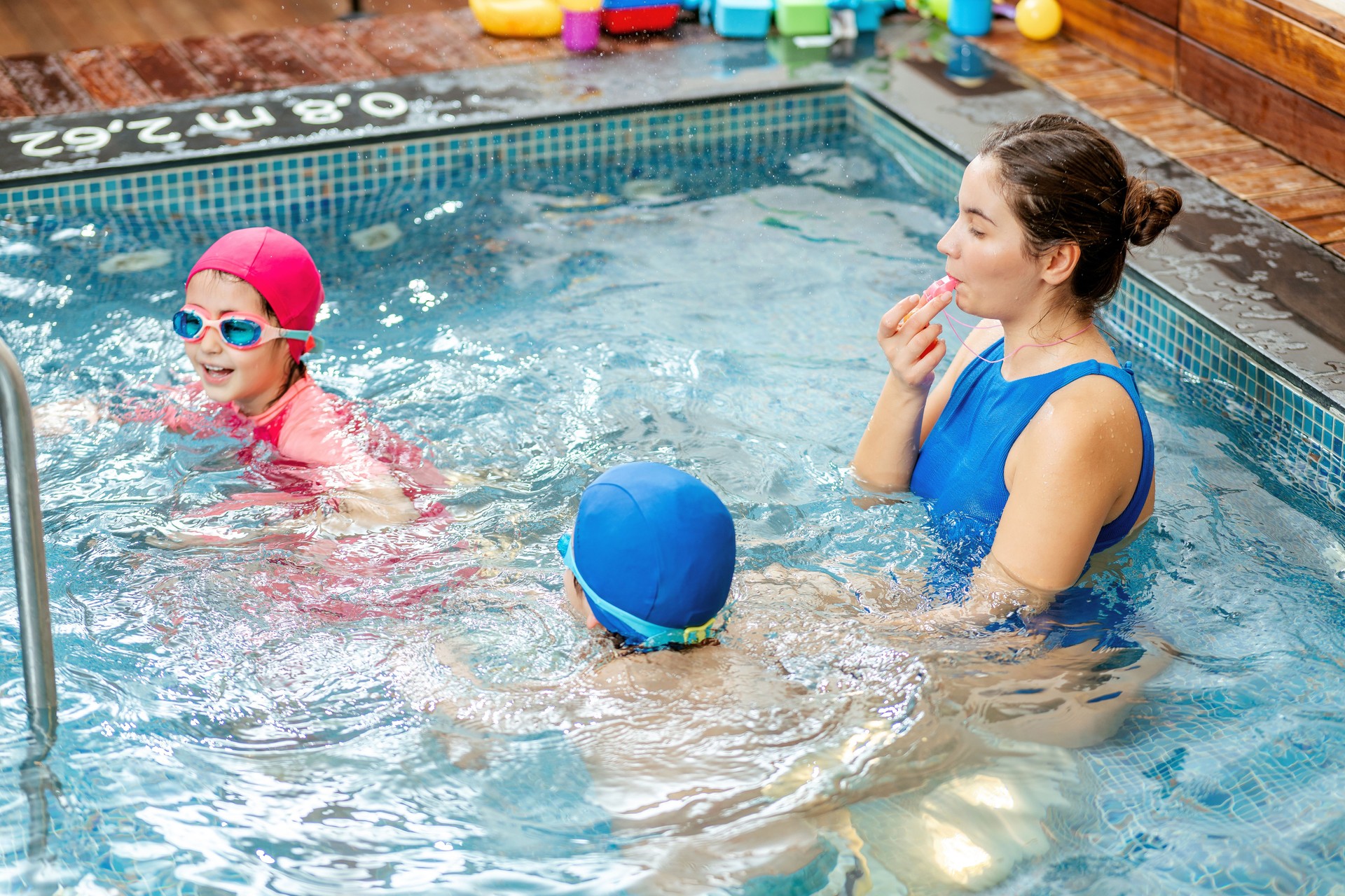 Female teacher teaches a boy and a girl to swim at a private swimming course