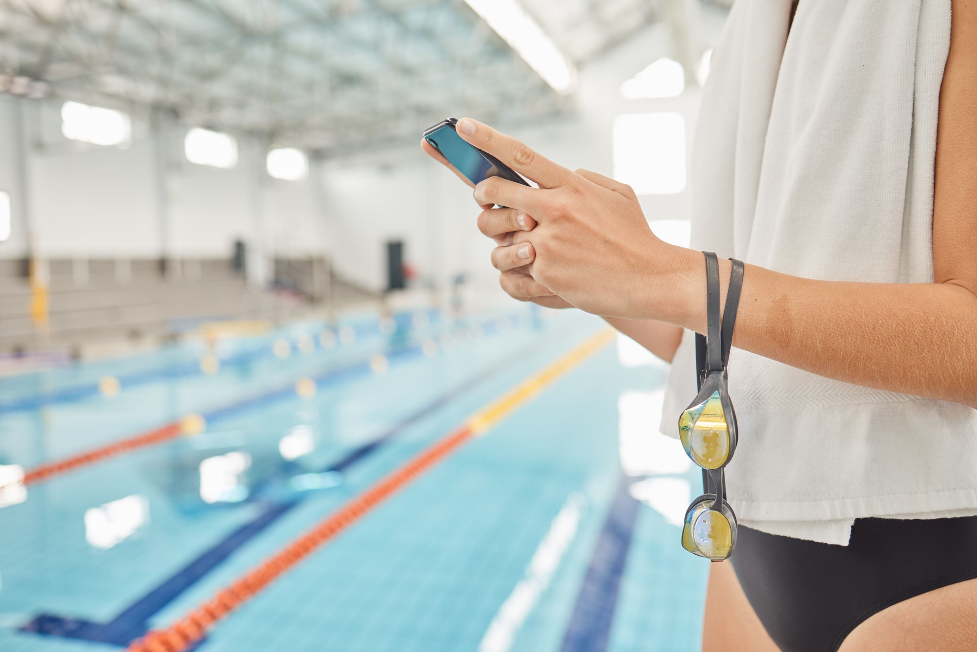 Hands, phone and athlete at swimming pool with social media, scrolling online or browsing internet after exercise. Swim, sports and woman with cellphone for communication after workout or training